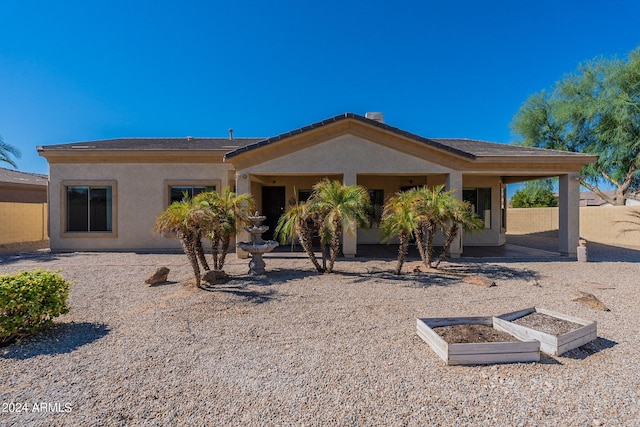 rear view of house with stucco siding, a patio area, and fence