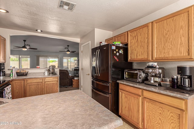 kitchen with kitchen peninsula, a textured ceiling, and black fridge