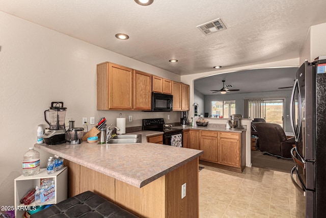 kitchen with ceiling fan, black appliances, a breakfast bar, kitchen peninsula, and sink