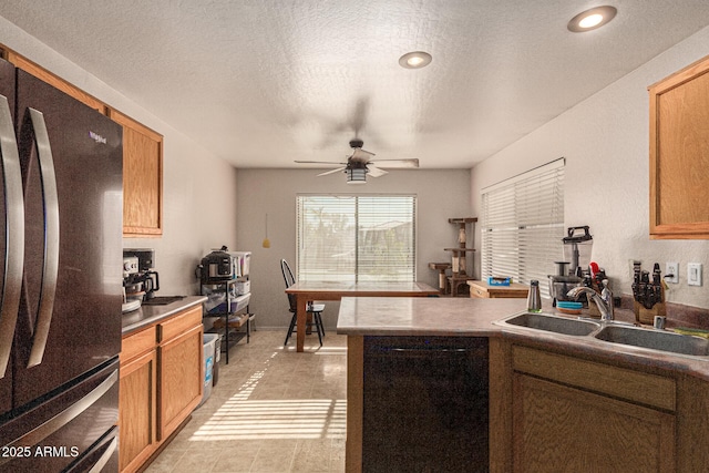 kitchen with ceiling fan, sink, stainless steel refrigerator, black dishwasher, and a textured ceiling