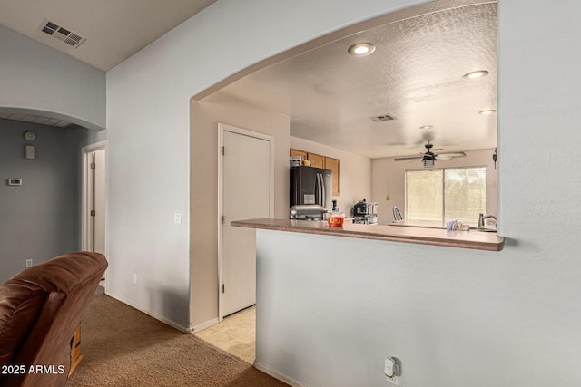 kitchen with light carpet, ceiling fan, a textured ceiling, and stainless steel refrigerator