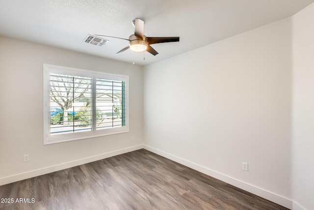 spare room featuring dark wood-style floors, visible vents, baseboards, and a ceiling fan