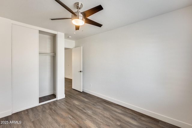 unfurnished bedroom featuring a closet, wood finished floors, a ceiling fan, and baseboards