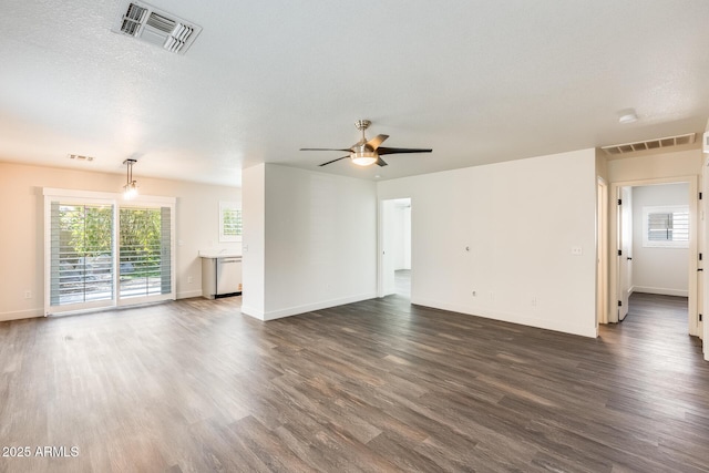 unfurnished living room featuring baseboards, visible vents, and dark wood finished floors