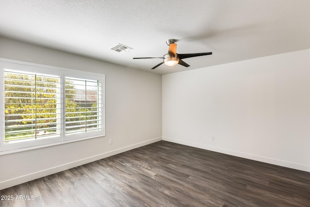 unfurnished room featuring dark wood-style floors, visible vents, a textured ceiling, and baseboards