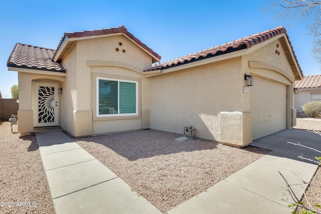 mediterranean / spanish home with a garage, concrete driveway, a tiled roof, and stucco siding