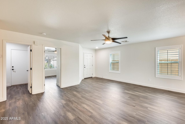 spare room featuring visible vents, dark wood-type flooring, a ceiling fan, and baseboards