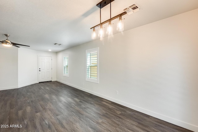 spare room featuring dark wood-type flooring, visible vents, and baseboards