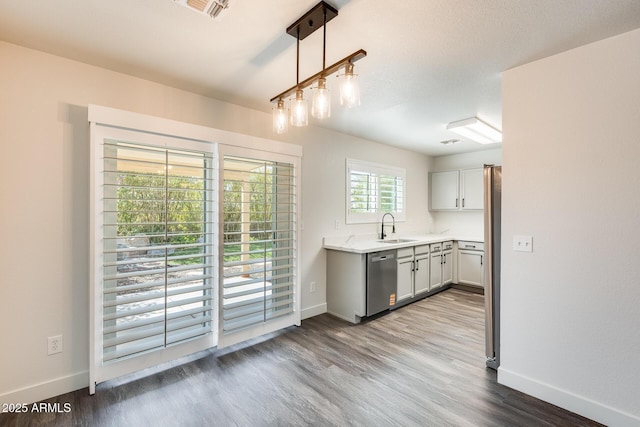 kitchen featuring stainless steel appliances, wood finished floors, a sink, and baseboards