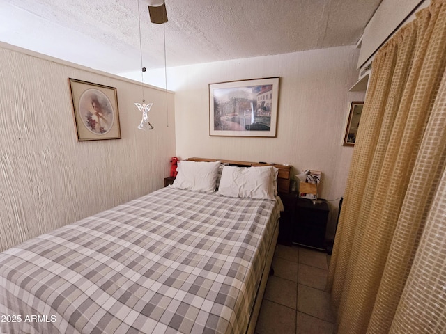 tiled bedroom with a ceiling fan and a textured ceiling