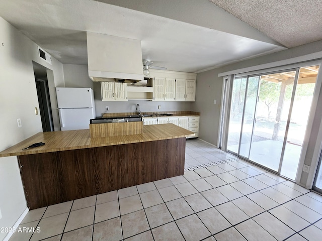 kitchen featuring visible vents, freestanding refrigerator, white cabinetry, ceiling fan, and wood counters