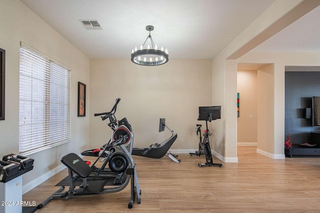 workout area featuring a notable chandelier and light hardwood / wood-style flooring