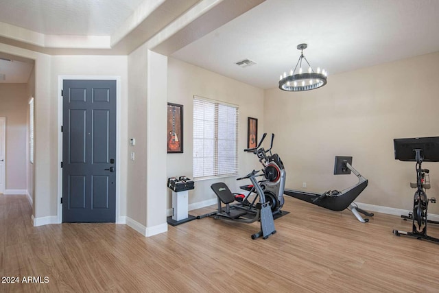 exercise area featuring a chandelier and light hardwood / wood-style flooring