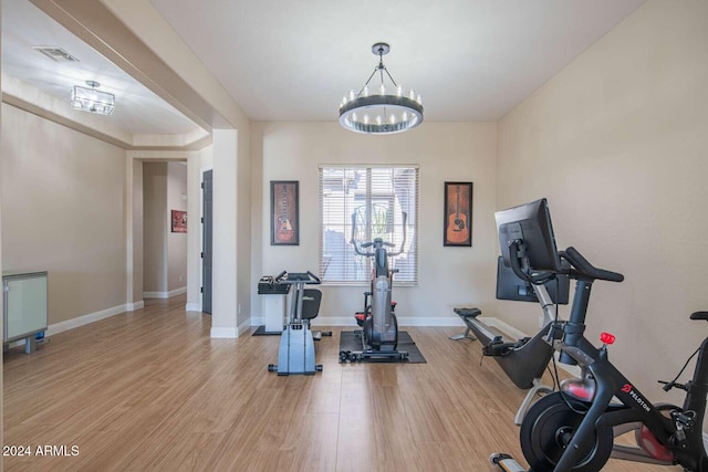 workout area with a chandelier and light hardwood / wood-style floors