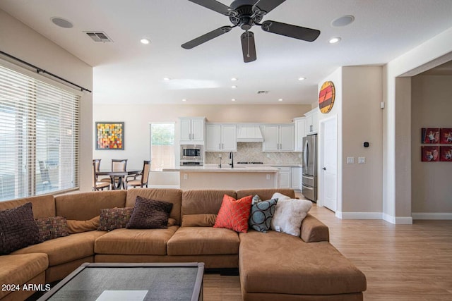 living room with ceiling fan, light hardwood / wood-style floors, and sink