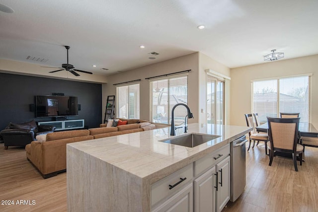 kitchen with white cabinetry, sink, light hardwood / wood-style flooring, stainless steel dishwasher, and a kitchen island with sink