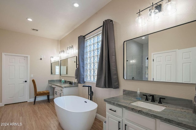 bathroom with a washtub, wood-type flooring, and vanity