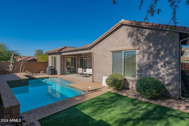 back of property with a fenced in pool, ceiling fan, a patio area, and a lawn