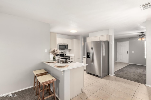 14919 W Hearn Cir, Surprise, AZ 85379 - kitchen featuring stainless steel appliances, a peninsula, light countertops, white cabinets, and a breakfast bar area