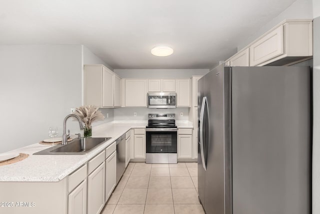14919 W Hearn Cir, Surprise, AZ 85379 - kitchen with stainless steel appliances, a sink, a peninsula, and light tile patterned floors