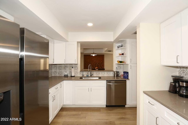 kitchen with backsplash, sink, light wood-type flooring, white cabinetry, and stainless steel appliances