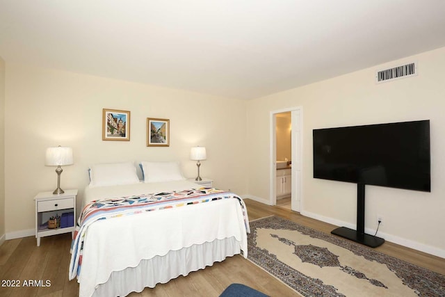 bedroom featuring wood-type flooring and ensuite bath