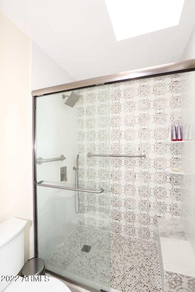 bathroom featuring walk in shower, a skylight, and toilet