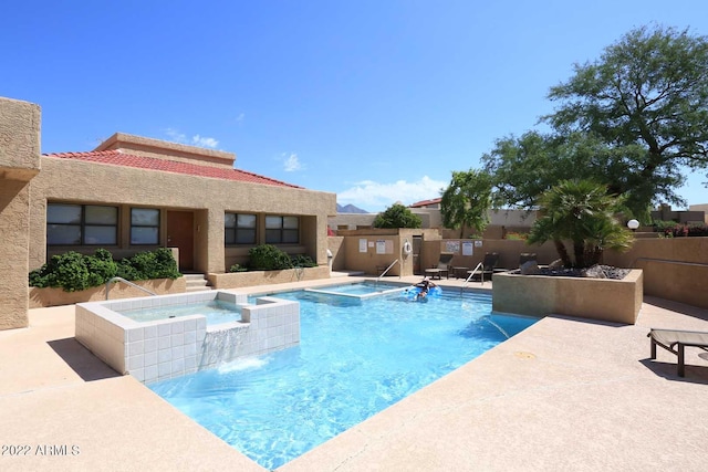 view of pool with a patio, pool water feature, and a hot tub