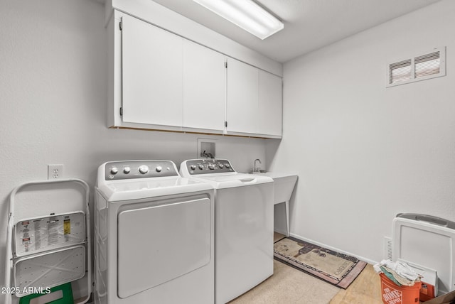 clothes washing area with cabinets and washing machine and clothes dryer