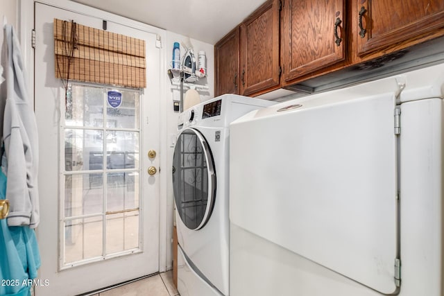 washroom featuring washer / clothes dryer, light tile patterned floors, a healthy amount of sunlight, and cabinets