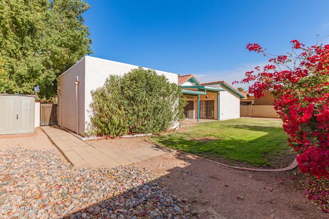 rear view of house with a yard and a storage unit