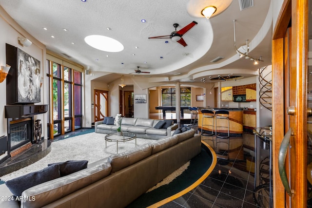 tiled living room with a premium fireplace, ceiling fan, and a textured ceiling