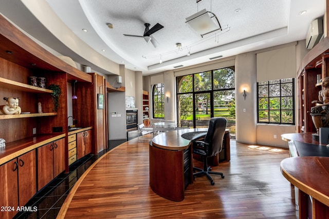 office featuring dark hardwood / wood-style flooring, plenty of natural light, a wall mounted AC, and a textured ceiling