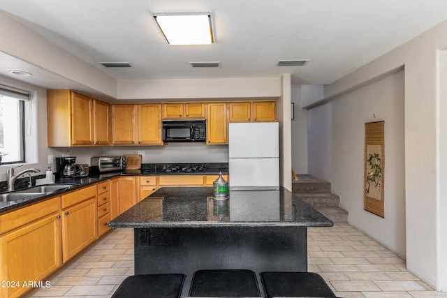 kitchen featuring dark stone counters, a center island, black appliances, and sink