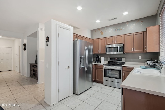 kitchen with appliances with stainless steel finishes, light tile patterned flooring, and sink