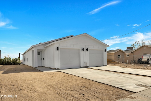 exterior space with driveway, an attached garage, board and batten siding, and fence