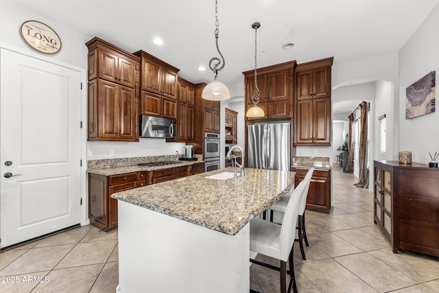 9285 E Canyon Vw, Scottsdale, AZ 85255 - kitchen featuring a sink, light tile patterned flooring, arched walkways, stainless steel appliances, and light stone countertops