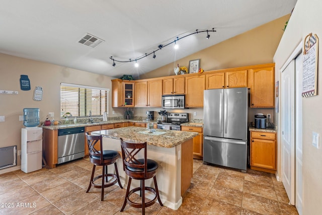 kitchen featuring visible vents, a kitchen island, stainless steel appliances, vaulted ceiling, and glass insert cabinets