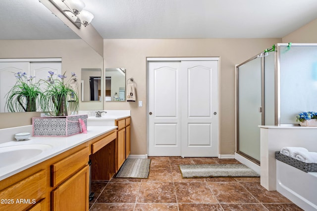 bathroom with baseboards, double vanity, a sink, a shower stall, and stone finish floor