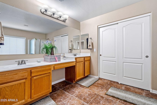 bathroom featuring double vanity, baseboards, and a sink