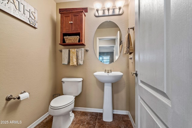 bathroom featuring baseboards, toilet, and tile patterned flooring