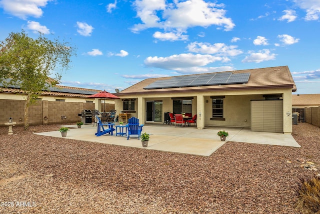 back of property with solar panels, a patio area, a fenced backyard, and stucco siding