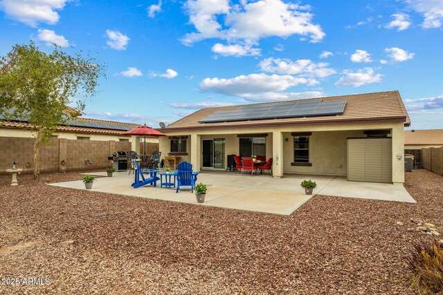 back of property with solar panels, a patio area, a fenced backyard, and stucco siding