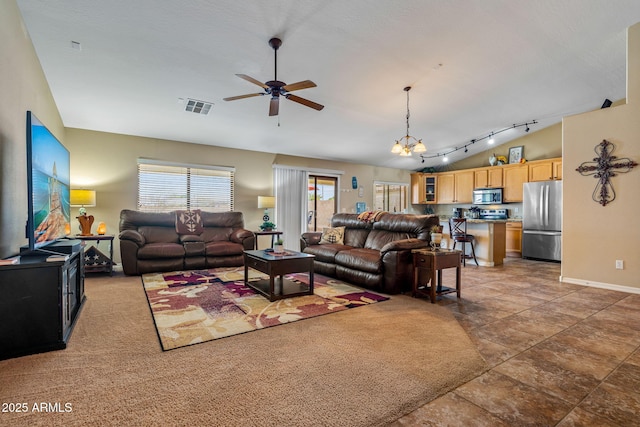 living area with visible vents, ceiling fan with notable chandelier, baseboards, rail lighting, and lofted ceiling