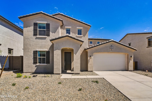 mediterranean / spanish home featuring a tile roof, driveway, a garage, and stucco siding
