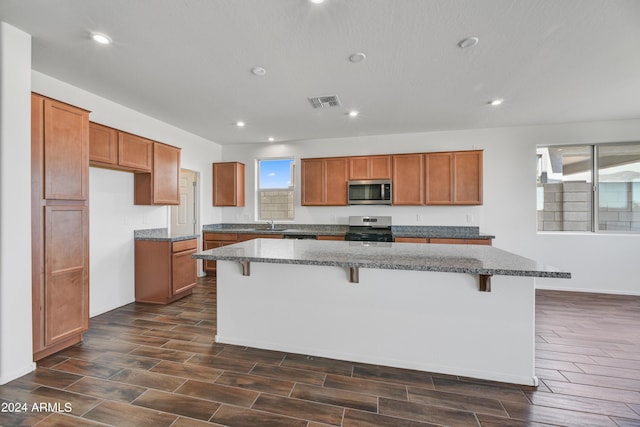 kitchen featuring brown cabinets, stainless steel appliances, recessed lighting, and a center island