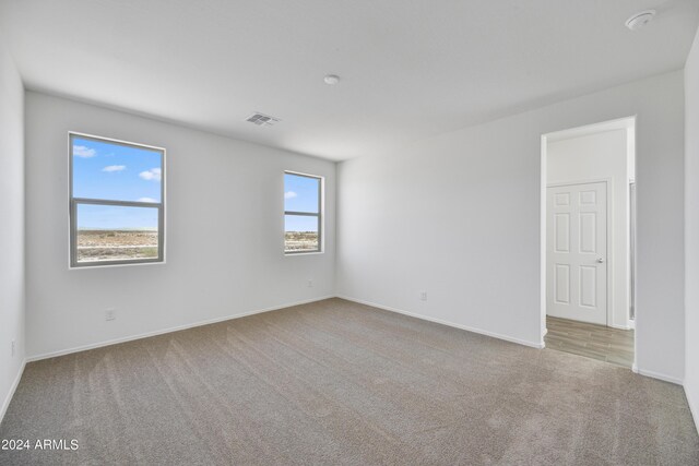 carpeted empty room featuring visible vents and baseboards