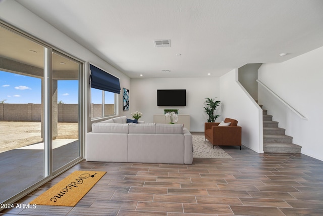living area with wood tiled floor, recessed lighting, visible vents, and stairway