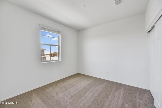 empty room featuring visible vents, carpet floors, and baseboards