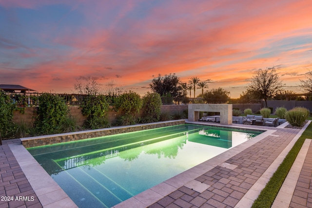 pool at dusk featuring a patio